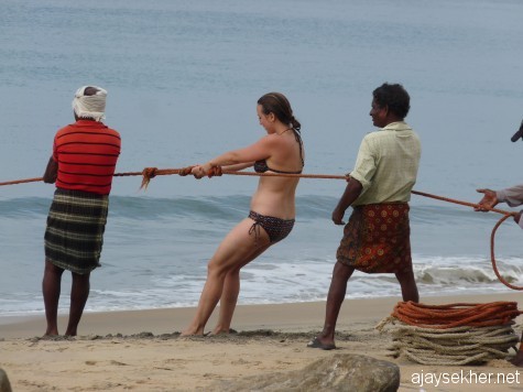 Lady Christ among the fisher folk: A white woman helping the fishermen to pull the loop-net from the sea at Black Beach, Varkala.