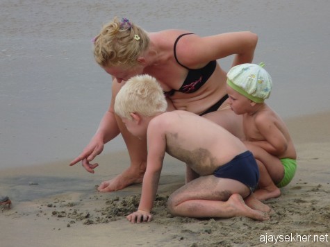 A European mother showing crabs and marine life forms to her curious little ones on the Black Beach, Varkala. 26 Dec 2012