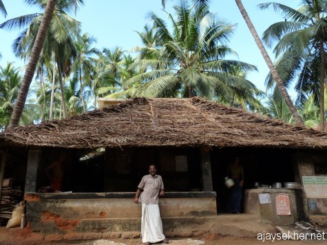 A humble coconut leaf thatched tea shop in Ezhava Thuruthy.  Mr Premdas Ponnani a local poet and artist before the humane hut amidst astonishing coconut groves by the Perar.
